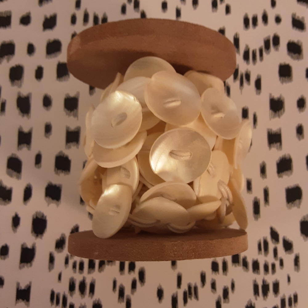 Wooden Spool of mother-of-pearl buttons.